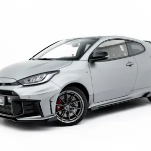 Grey sports hatchback car shown from the front-left, with prominent grille and alloy wheels on a white background (GR badge visible).