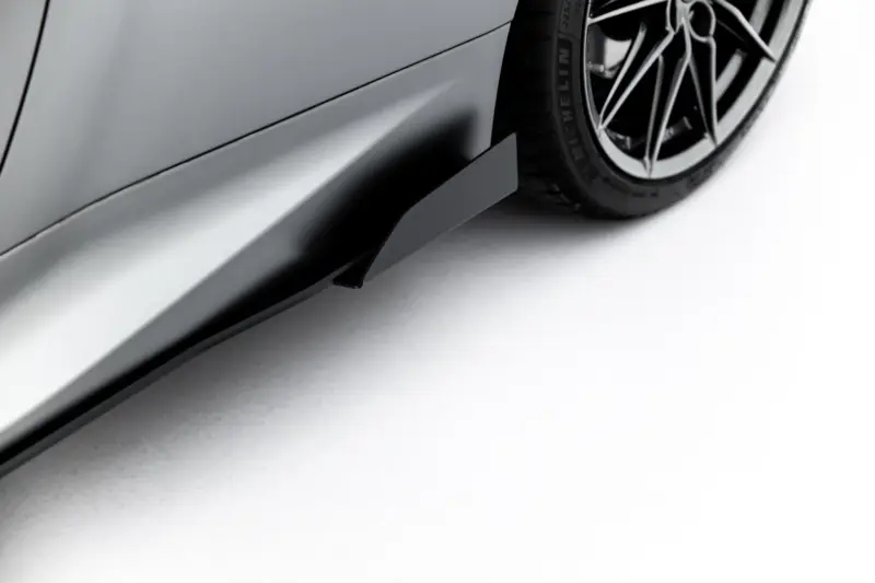 Close-up of a car's side panel and wheel, showing a gray body and black alloy wheel on the right.