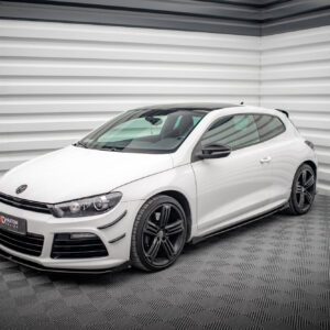 White Volkswagen hatchback photographed in a showroom with corrugated gray walls, front-left angle showing black alloy wheels and sleek design