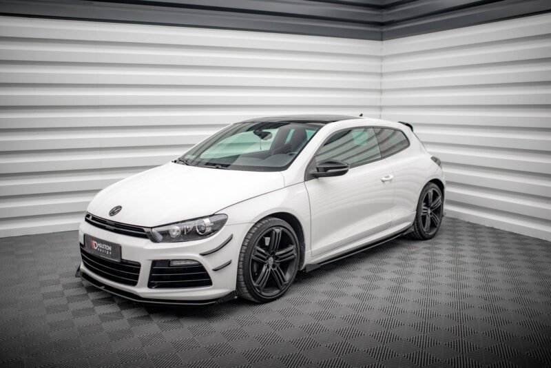 Front-left three-quarter view of a white sports hatchback in a studio with striped gray walls behind it, showroom lighting clear on the car.