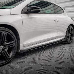 Close-up side view of a white car showing the door, window, and black alloy wheels in a studio setting.