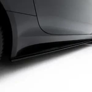 Close-up of a gray sports car's side panel and front wheel, highlighting sleek body lines and glossy finish.
