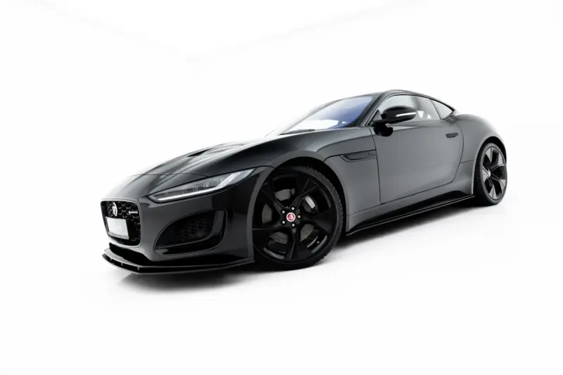 Low-angle side view of a sleek gray Jaguar sports car on a white background that emphasizes its curves and wheels.