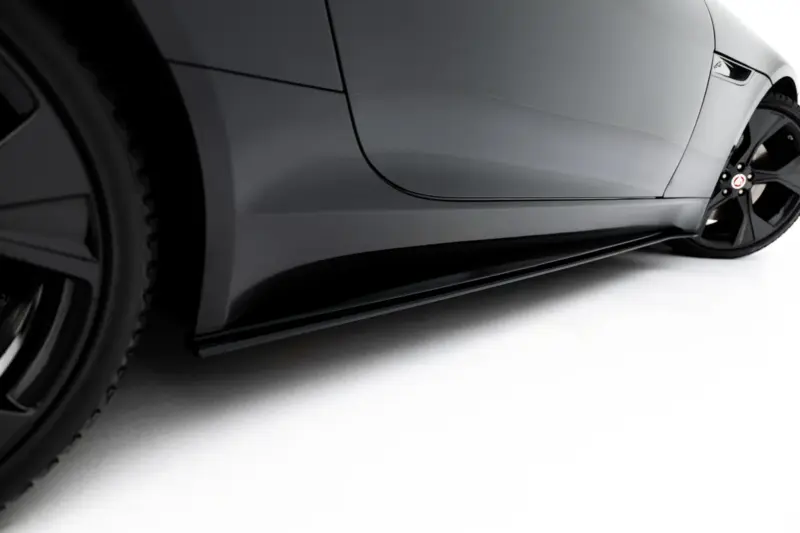 Close-up of a gray sports car's side panel and wheel, showing glossy paint and a black alloy rim.