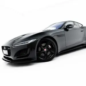 Low-angle front-left view of a sleek grey Jaguar sports car on a white background, highlighting wheels and grille.