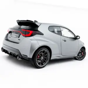 Rear three-quarter view of a silver hatchback with a large rear spoiler and black alloy wheels, in a bright studio setting.