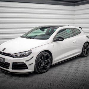 Front three-quarter view of a white Volkswagen hatchback in a studio with gray corrugated walls and black alloy wheels, on a checkered floor.