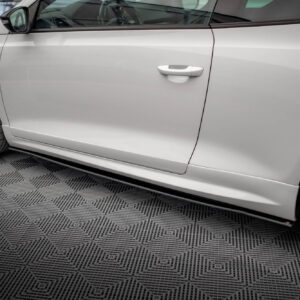 White car parked indoors; side door, handle, and front wheel with a black alloy rim visible in a showroom setting.