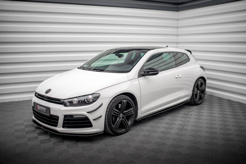 White Volkswagen car, front-left view, parked in a showroom with striped metal walls and dark alloy wheels.