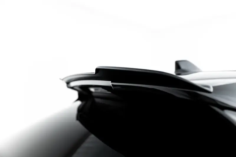 Close-up of a glossy black automotive surface with smooth, curved lines against a white background.