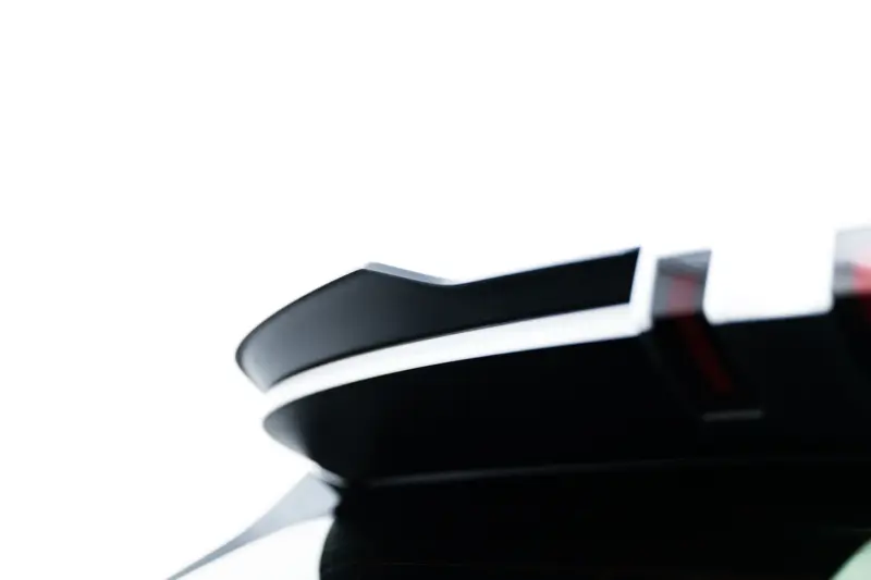 Close-up of a glossy black surface with curved edges and metallic accents, abstract and minimal.