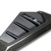 35jpg - OPSHOLDERS Close-up of a carbon fiber car trim piece featuring an M Performance badge with blue, dark blue, and red stripes.