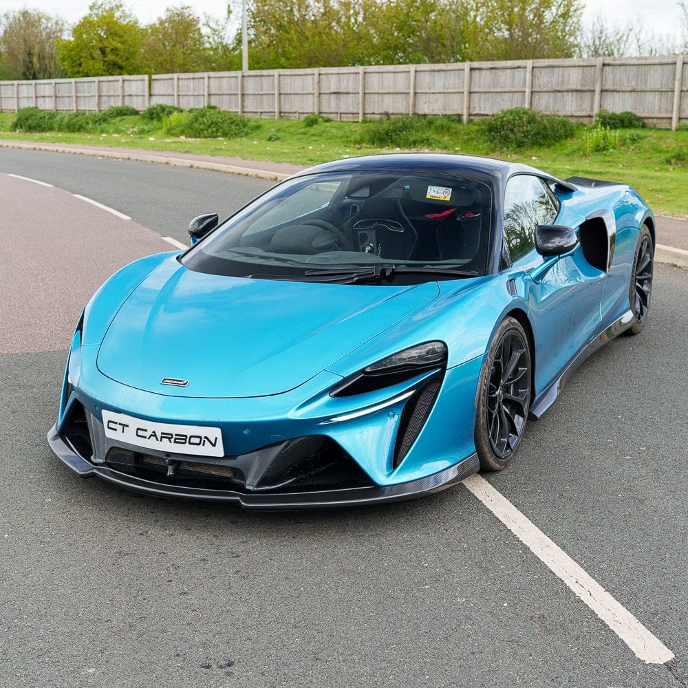 Artura_Web_CT_Carbon_170426_19jpg - OPSHOLDERS Blue McLaren-style sports car parked diagonally in a parking lot, front view with black carbon accents and large front splitter.