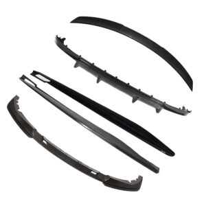 Set of carbon fiber automotive exterior trim pieces (front lip, side skirts) laid out for a body kit installation