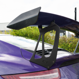 Purple sports car with a large carbon-fiber rear wing mounted on the trunk for downforce and aerodynamics.