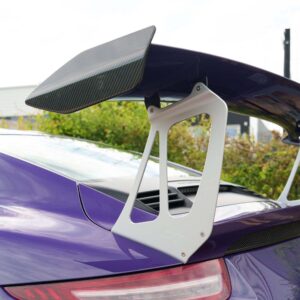 Rear spoiler with carbon fiber endplate mounted on a purple sports car, showing aerodynamic wing support.
