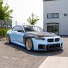 DSC00429jpg - OPSHOLDERS Blue BMW coupe with carbon fiber hood and gold mesh wheels parked outside a modern building with number 18 visible, showing a modified stance.