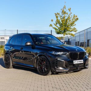 Black BMW SUV with a carbon fiber front bumper parked on a paved lot, showing glossy finish and large alloy wheels.