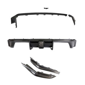 Set of automotive bumper parts including a carbon-fiber rear bumper, trim pieces, and splitter sections laid out separately for assembly.