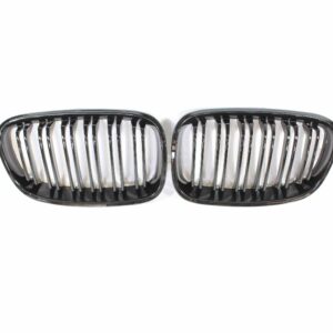 Two black automotive grilles with vertical chrome slats placed side by side on a white background