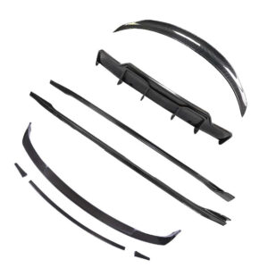 Disassembled carbon fiber car aero kit components: front lip, side skirts, rear spoiler pieces, and related fragments laid out in pieces.