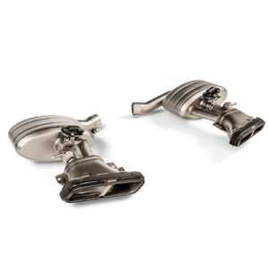 Two stainless steel car exhaust mufflers with curved pipes on a black background