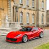Red Ferrari sports car parked on a cobblestone driveway beside a statue and ornate blue street lamp in front of a beige historic stone building.](https://example)