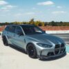g81_-4jpg - OPSHOLDERS Silver BMW wagon with black aftermarket wheels and a carbon front splitter parked on a rooftop parking lot under a blue sky.