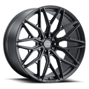 Matte black multi‑spoke alloy wheel with a complex angular spoke pattern and center cap marked MV FORGED