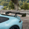 switzerland_porschegt3_1x1_CTCarbon_190626_06jpg - OPSHOLDERS Rear view of a light blue sports car with a large black spoiler parked near a chain-link fence and an overpass.