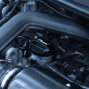 10-14-tsi-billet-dipstick_53400021124_o-1jpg - OPSHOLDERS Close-up of a car's engine bay focusing on the air intake tube, oil filler cap, and nearby wiring harness.