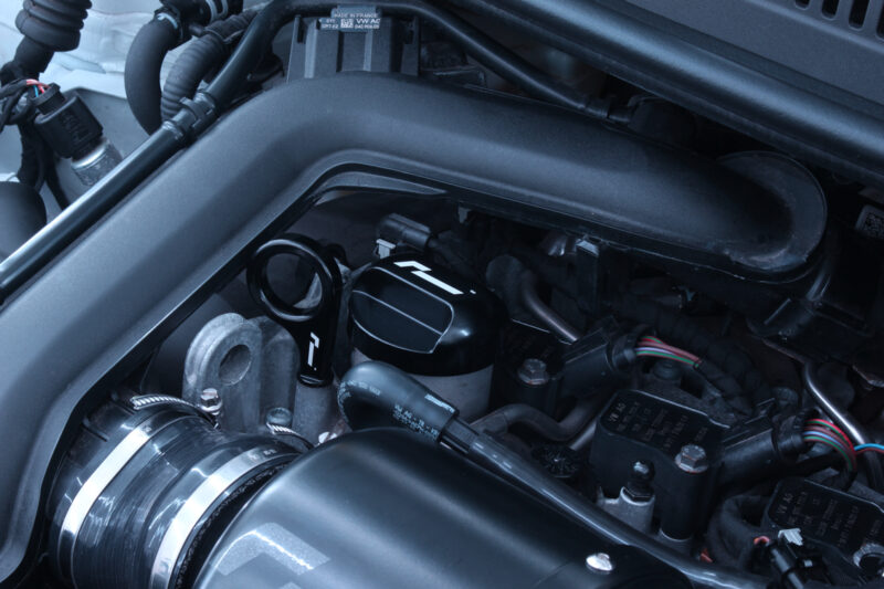10-14-tsi-billet-dipstick_53400021124_o-1jpg - OPSHOLDERS Close-up of a car's engine bay focusing on the air intake tube, oil filler cap, and nearby wiring harness.