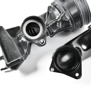 Close-up of an automotive shock absorber/strut assembly with mounting bracket and spring visible, shown in grayscale.