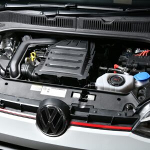 Front view of a VW with the hood open, showing the engine bay including the air intake box and right-side battery.