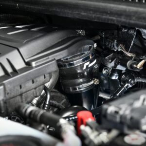 Close-up of a car engine bay showing a turbocharger and wiring harness under the hood.