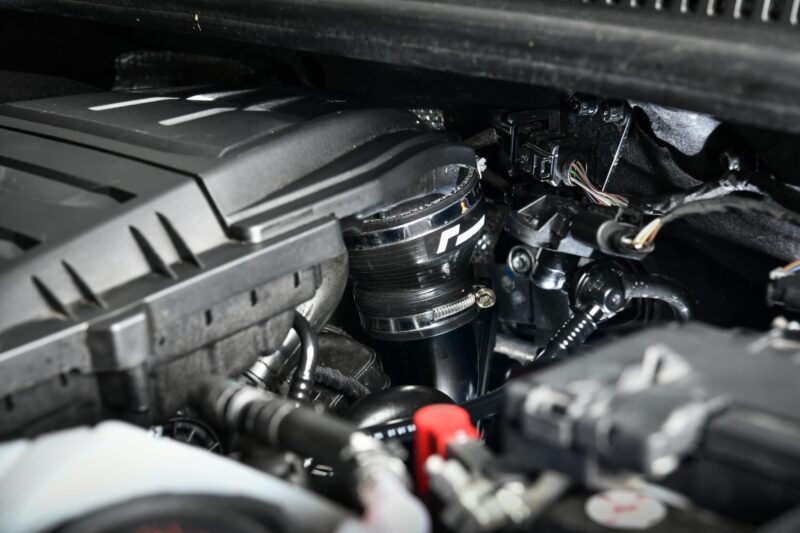 Close-up of a car engine bay showing a turbocharger and wiring harness under the hood.