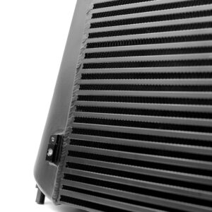 Close-up of a black metal radiator/heat exchanger with horizontal fins, seen in grayscale, with a small cable and mounting bracket at the edge.