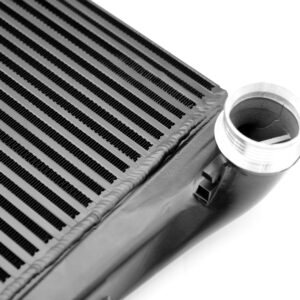 Close-up of an automotive heater core showing parallel aluminum fins and a cylindrical inlet/outlet pipe