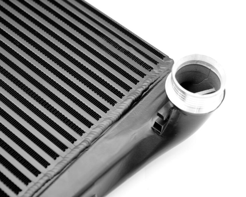 Close-up of an automotive heater core showing parallel aluminum fins and a cylindrical inlet/outlet pipe