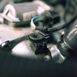 25-tfsi-engine-cover-grommets_53353013820_ojpg - OPSHOLDERS Close-up of a small black electrical connector with colorful wires inside a metal housing.