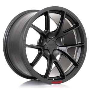 Dark gray alloy car wheel with a multi-spoke design and a small red accent near the rim.