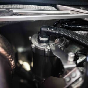 Close-up of a car’s engine bay showing braided hoses, metal fittings, and dark plastic connectors.