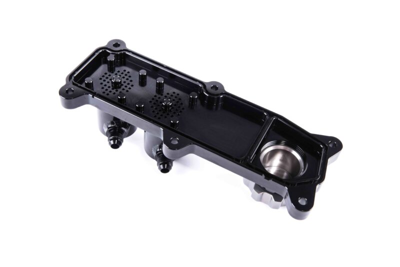 Black plastic enclosure with multiple posts and a perforated base, shown at an angle against a white background, likely a housing component for electronics or automotive systems.