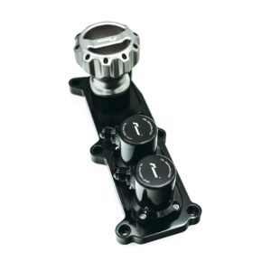 Close-up of a metallic handlebar clamp/dial on a black bicycle/motorcycle component with adjustment knobs.