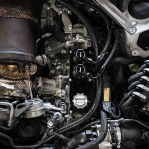 Close-up of a car engine bay showing a turbocharger, hoses, and wiring.