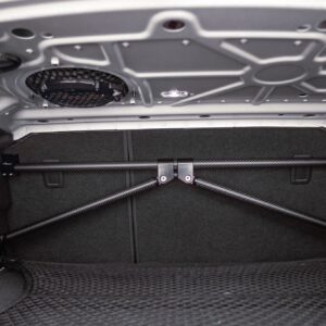 51286203405_53812351a2_k-1jpg - OPSHOLDERS Interior of a car trunk viewed from below, showing the underside of the trunk lid with structural crossbars, a circular vent/grill, and bundled support rods against dark carpeted walls