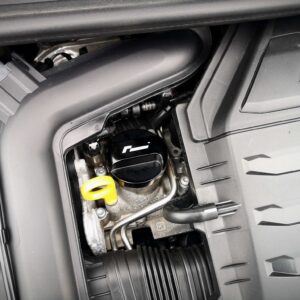 Open vehicle compartment showing engine bay area with hoses, wiring, and a yellow dipstick handle visible near the edge of the opening (likely a maintenance space).