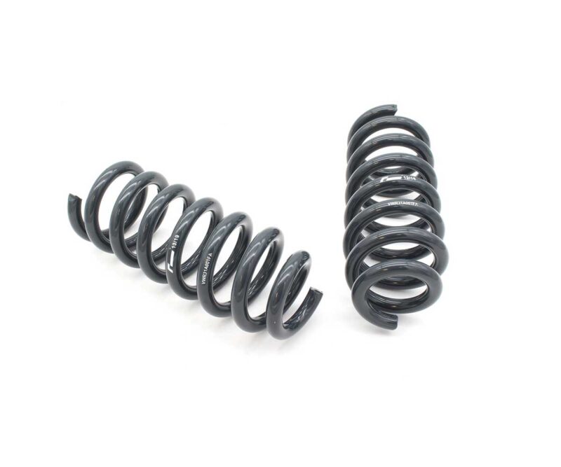 53272464673_52be6e73fd_k-1jpg - OPSHOLDERS Two black metal coil springs on a white background, one horizontal and one vertical, likely vehicle suspension springs.