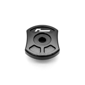 Close-up of a black plastic component with a circular central recess and two gray grip pads at the bottom, partially showing a logo on the top surface.