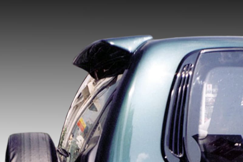 A-155_1jpg - OPSHOLDERS Close-up of a teal car with a bent hood and exposed wheel, shown against a gray gradient background. The image is a cropped side view showing part of the windshield and wheel area.